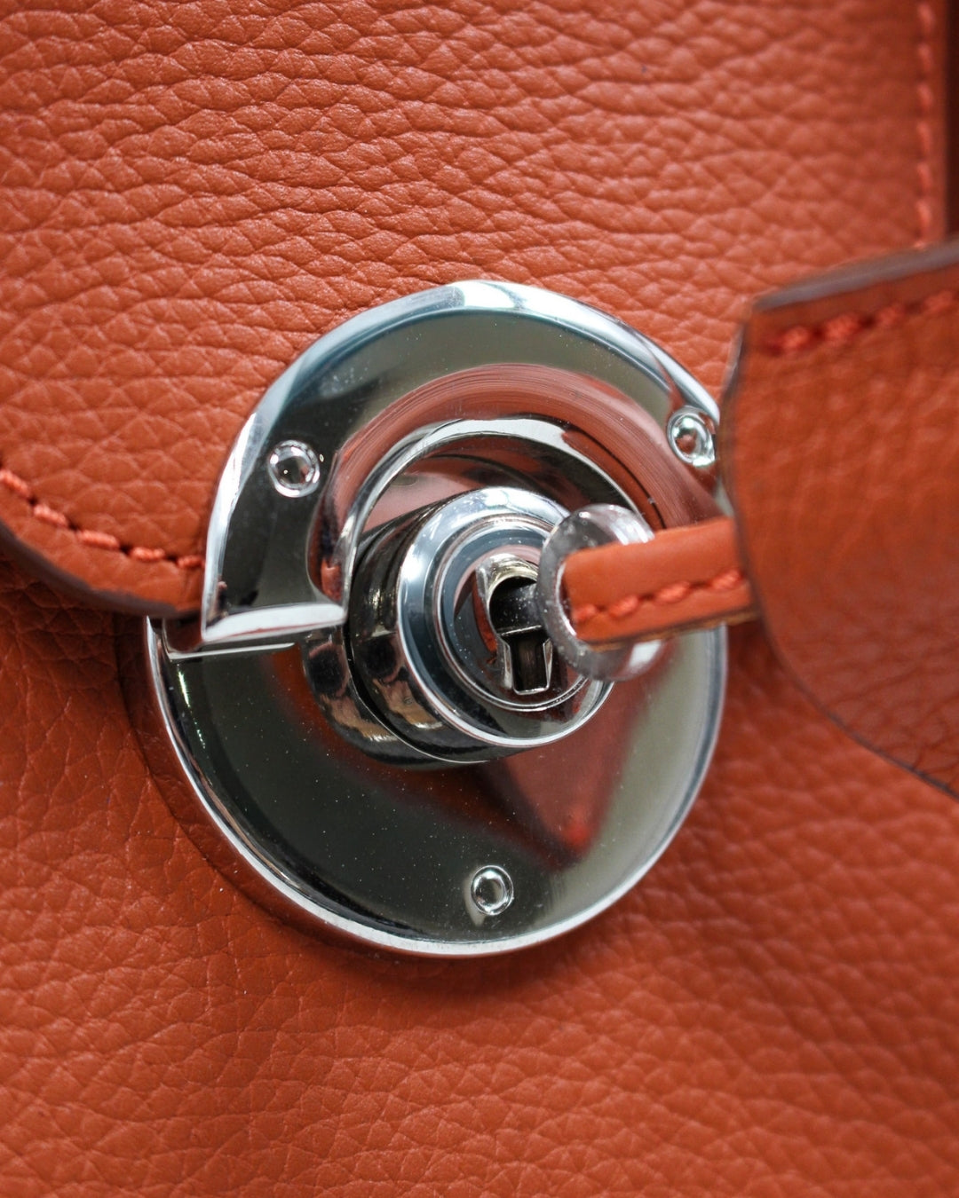 Détail fermoir rond doré mini sac Cortina cuir orange