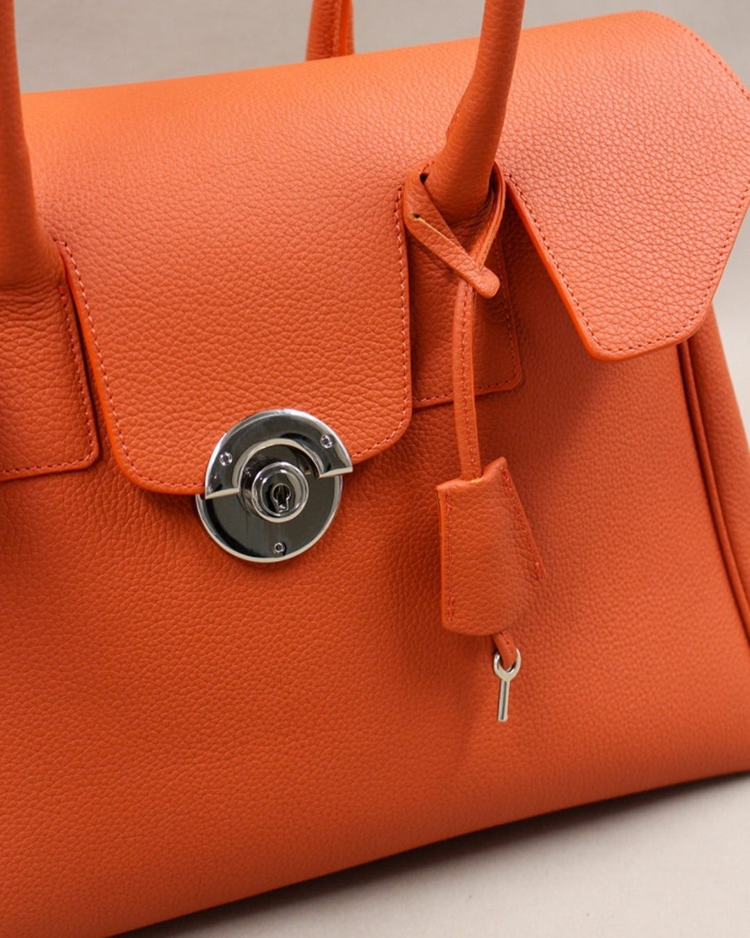 Détail fermoir rond doré sac Cortina cuir orange