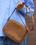 Femme portant minaudière cuir camel en bandoulière