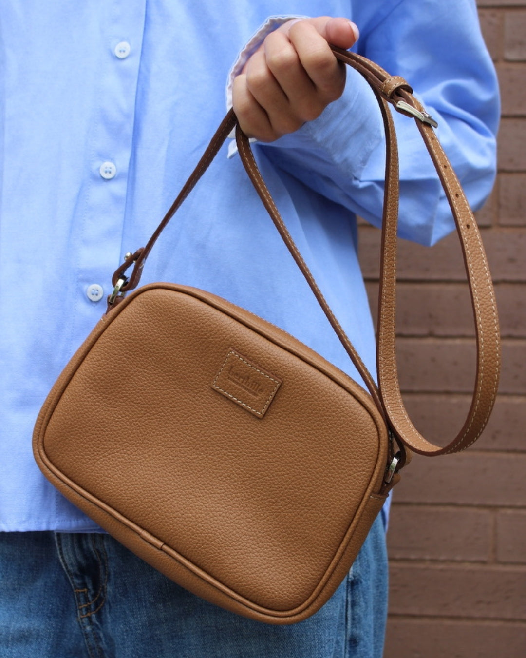 Femme portant minaudière cuir camel en bandoulière