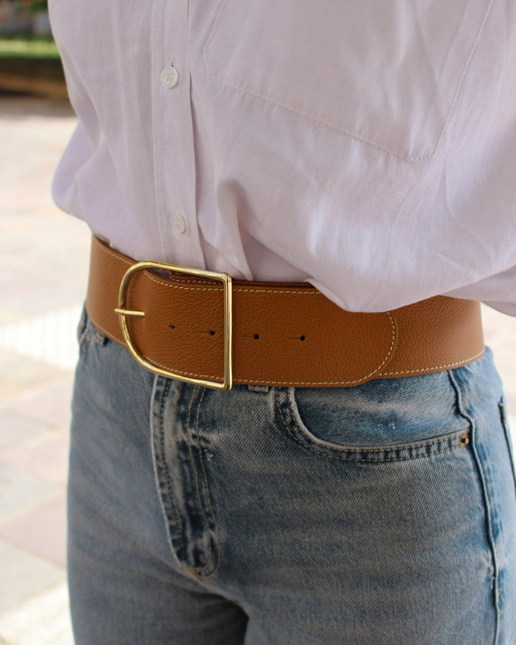 Femme portant une ceinture demi-lune cuir camel sur jean