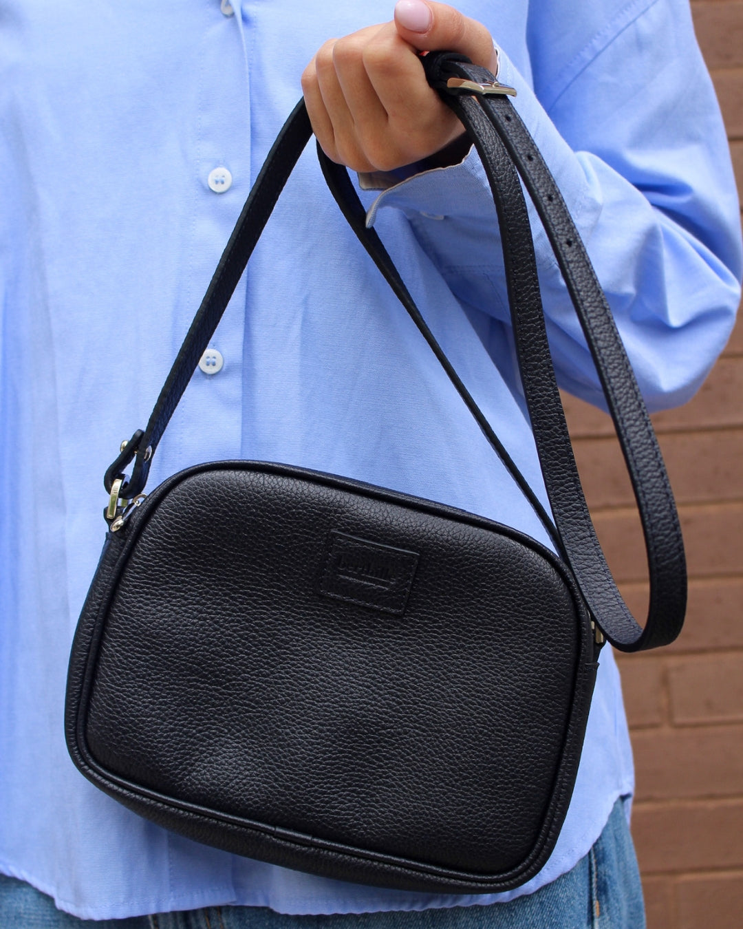 Minaudière cuir noir portée épaule tenue décontractée