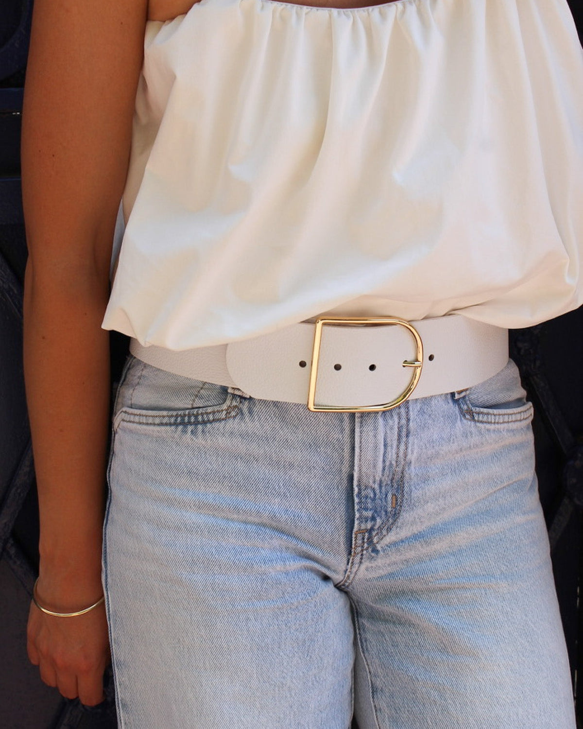 Ceinture berthille demi lune en cuir couleur blanche porter par une femme avec un top blanc et un jean 