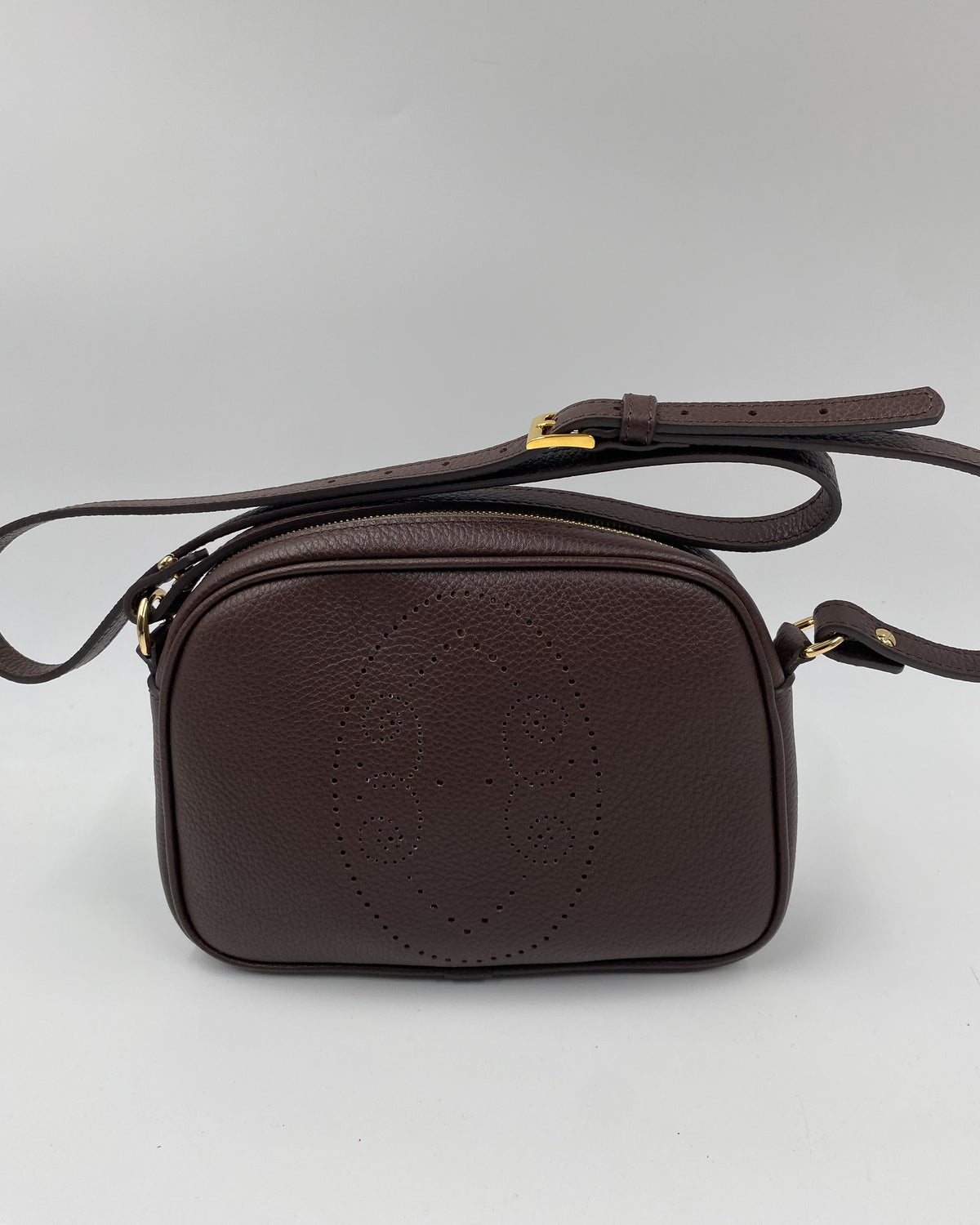 Pochette Trianon en cuir chocolat vue de face, motif perforé bout fleuri et bandoulière réglable, fabriquée en France par Berthille