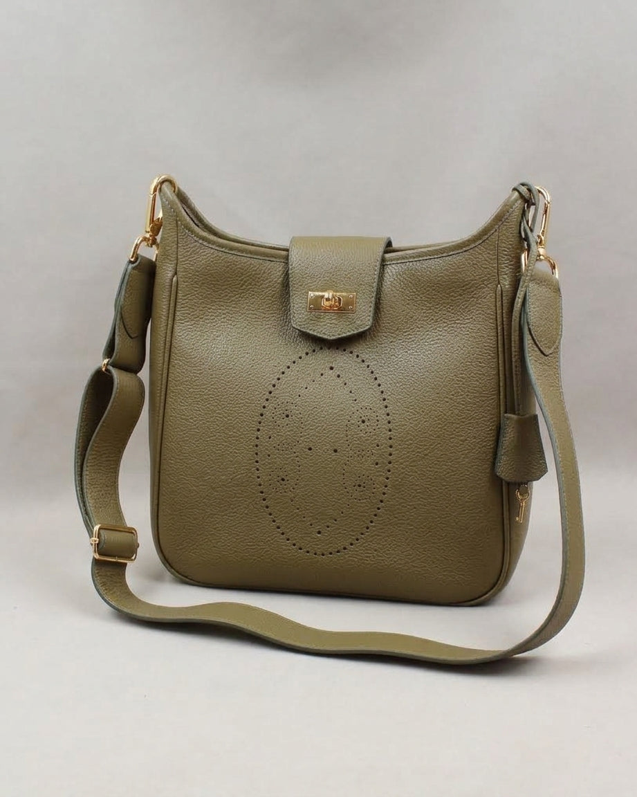 Sac Trianon grand format en cuir kaki vue de trois quarts, motif perforé bout fleuri, fermoir tournant doré, clochette en cuir et large bandoulière réglable, fabriqué en France par Berthille