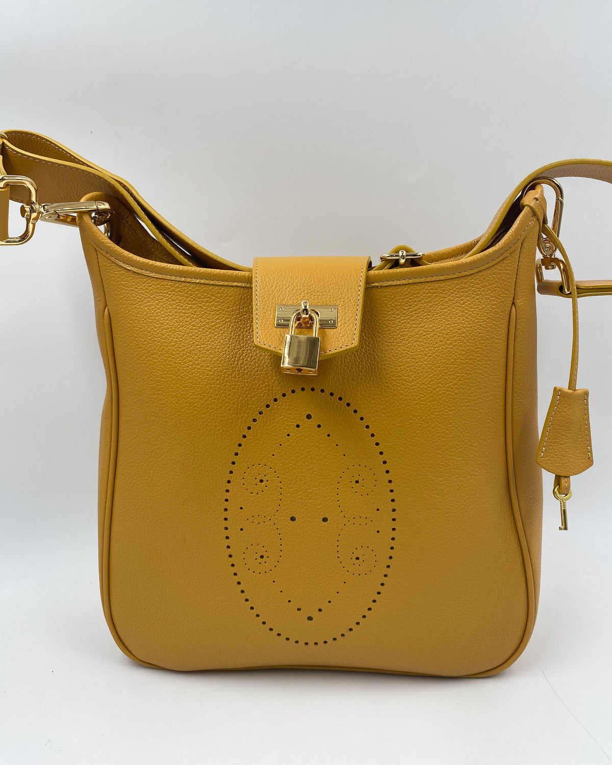 Sac Trianon grand format en cuir jaune moutarde vue de face, motif perforé bout fleuri, cadenas doré, clé et clochette en cuir, fabriqué en France par Berthille